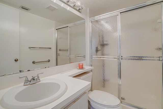 bathroom with vanity, toilet, and a shower with door