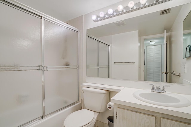 full bathroom featuring vanity, shower / bath combination with glass door, and toilet