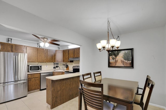 kitchen featuring sink, hanging light fixtures, light tile patterned floors, appliances with stainless steel finishes, and kitchen peninsula