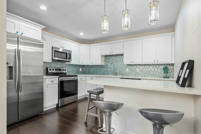 kitchen with a kitchen bar, decorative light fixtures, dark wood-style flooring, and appliances with stainless steel finishes