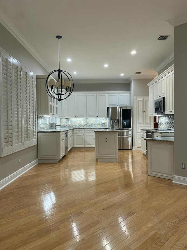 kitchen featuring a center island, a chandelier, pendant lighting, stainless steel appliances, and white cabinets