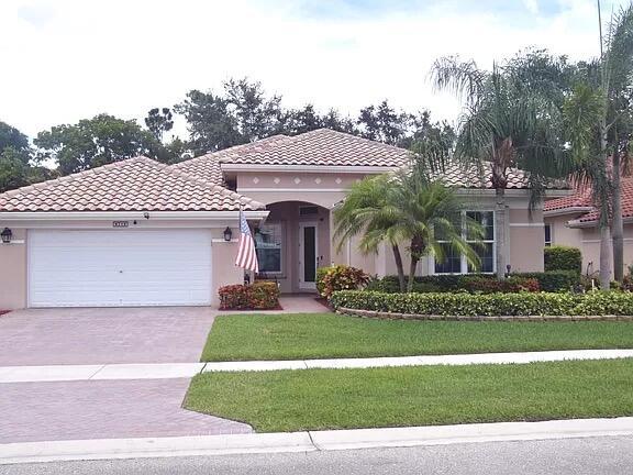 mediterranean / spanish-style house featuring stucco siding, an attached garage, a front yard, and a tile roof