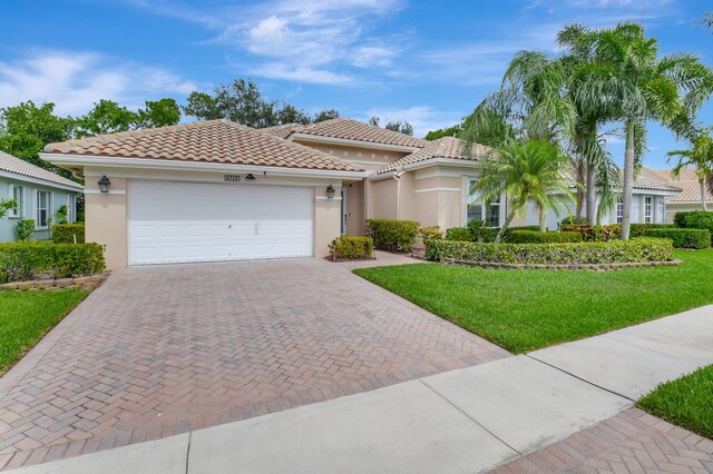 6718 Jog Palm Dr, Boynton Beach, FL 33437 - mediterranean / spanish-style house featuring stucco siding, decorative driveway, a front yard, an attached garage, and a tile roof