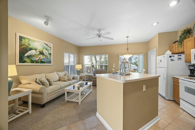 kitchen with light tile patterned floors, ceiling fan, a kitchen island, pendant lighting, and white appliances