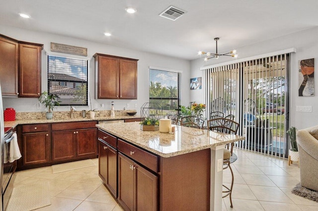 kitchen featuring electric range, a kitchen breakfast bar, a center island, a notable chandelier, and light stone countertops