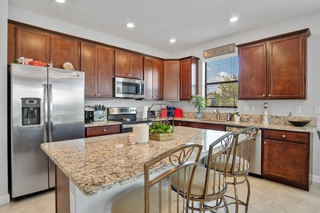 kitchen with stainless steel appliances, light stone countertops, a kitchen island, and a kitchen breakfast bar