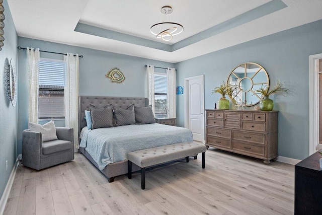 bedroom featuring light hardwood / wood-style flooring and a tray ceiling