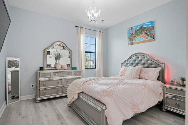 bedroom featuring an inviting chandelier and light hardwood / wood-style floors