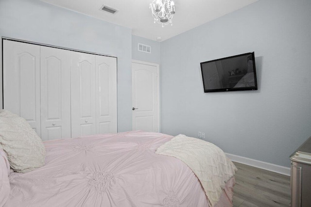 bedroom with hardwood / wood-style flooring, a notable chandelier, and a closet