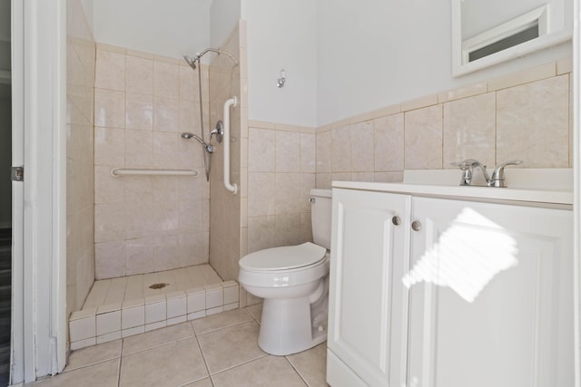 bathroom featuring a tile shower, tile walls, vanity, toilet, and tile patterned floors