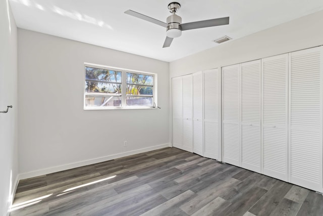 unfurnished bedroom featuring ceiling fan, dark hardwood / wood-style floors, and two closets