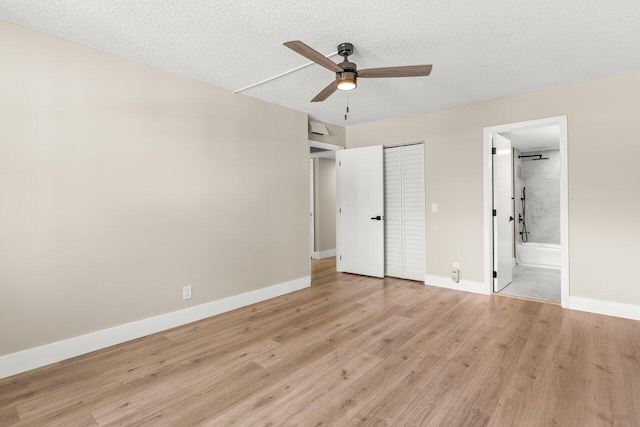 unfurnished bedroom with light hardwood / wood-style flooring, a closet, a textured ceiling, and ensuite bathroom