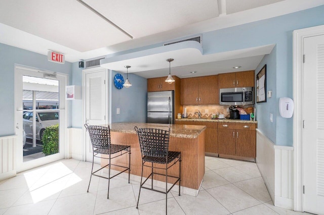 kitchen with pendant lighting, tasteful backsplash, sink, light tile patterned floors, and stainless steel appliances