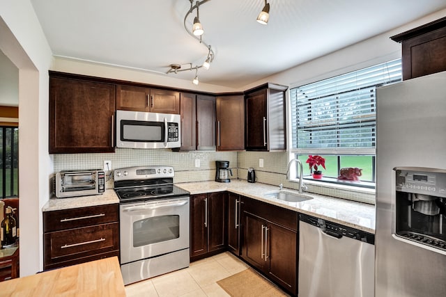 kitchen with light tile patterned floors, sink, stainless steel appliances, dark brown cabinetry, and decorative backsplash