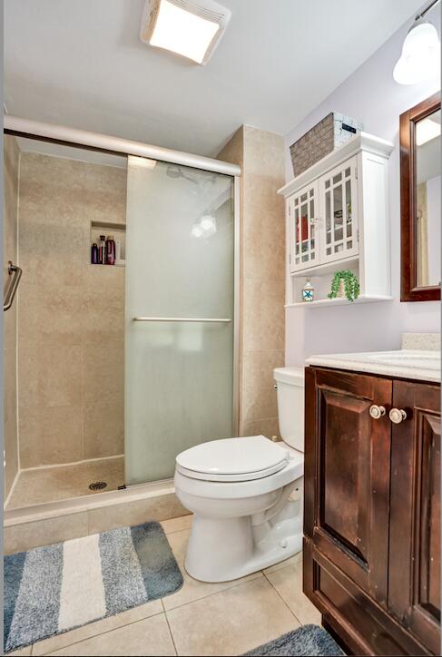 bathroom featuring vanity, tile patterned flooring, toilet, and walk in shower