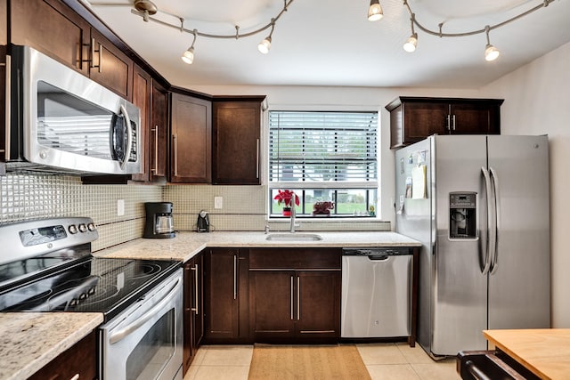 kitchen with stainless steel appliances, light stone countertops, decorative backsplash, light tile patterned floors, and sink