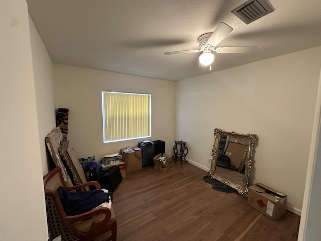 living area featuring wood-type flooring, a textured ceiling, and ceiling fan