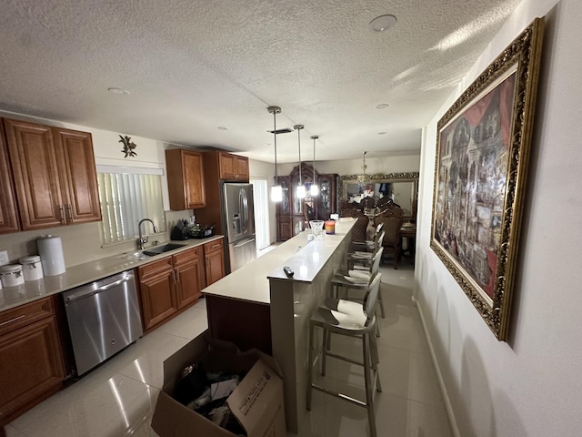 kitchen featuring a breakfast bar, sink, a center island, hanging light fixtures, and stainless steel appliances