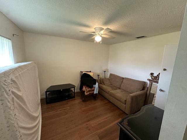 living room with ceiling fan, dark hardwood / wood-style floors, and a textured ceiling