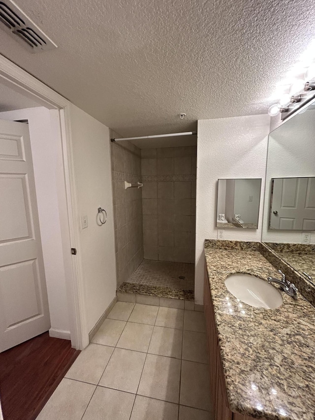 full bath with visible vents, tiled shower, and a textured ceiling