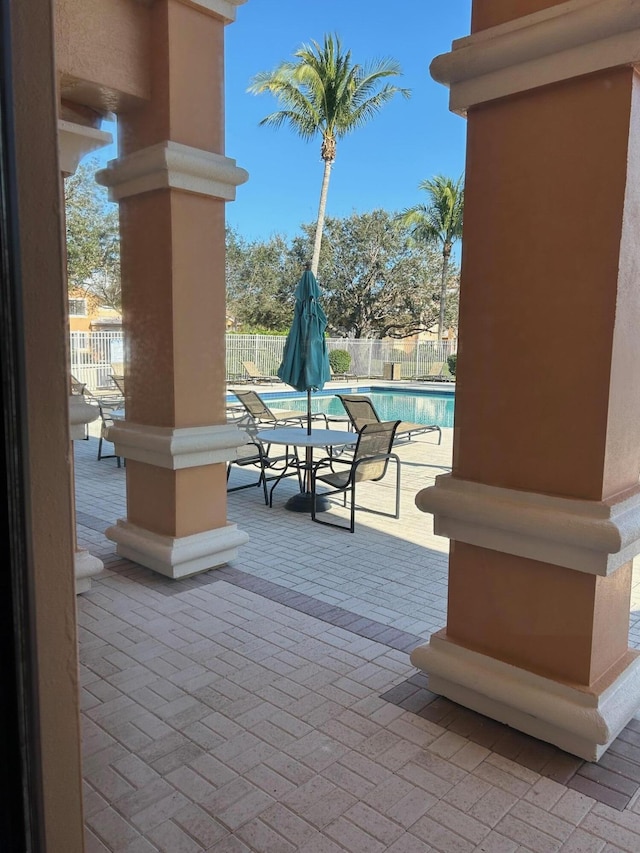 view of patio with a community pool and fence