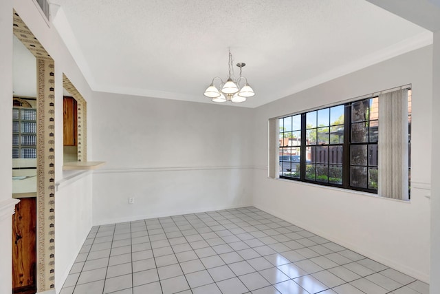 tiled spare room featuring crown molding, a textured ceiling, and a chandelier