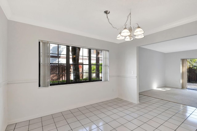 carpeted spare room featuring a chandelier