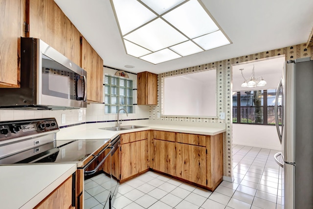 kitchen featuring sink, an inviting chandelier, hanging light fixtures, stainless steel appliances, and tasteful backsplash