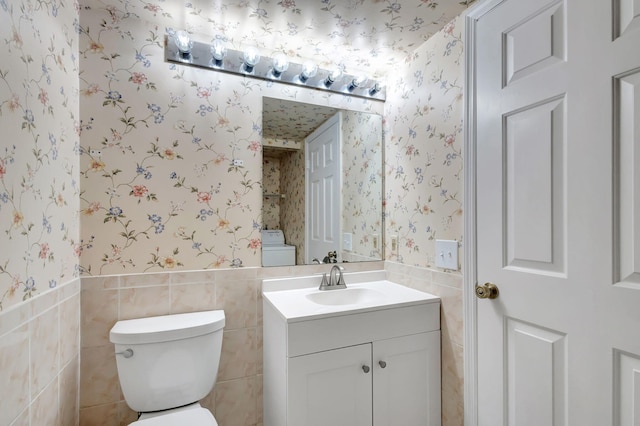 bathroom featuring vanity, tile walls, and toilet