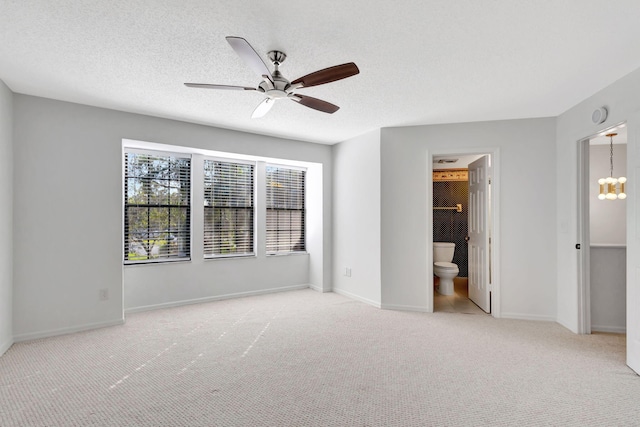 unfurnished bedroom featuring ensuite bathroom, ceiling fan with notable chandelier, light colored carpet, and a textured ceiling