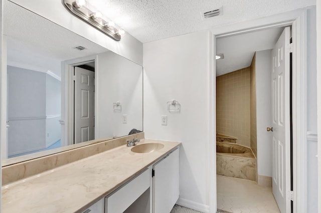 bathroom featuring vanity, tile patterned flooring, tiled bath, and a textured ceiling