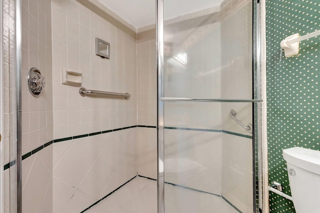 bathroom featuring toilet and a shower with shower door