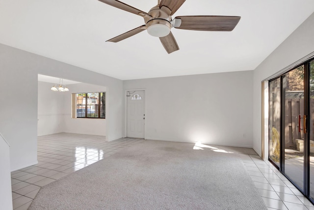 carpeted spare room with ceiling fan with notable chandelier