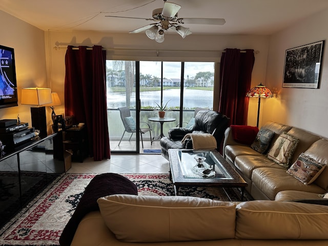 living area featuring a water view, light tile patterned floors, and a ceiling fan