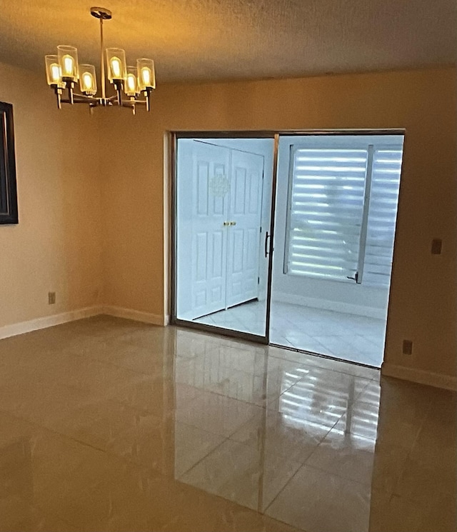 tiled spare room featuring an inviting chandelier