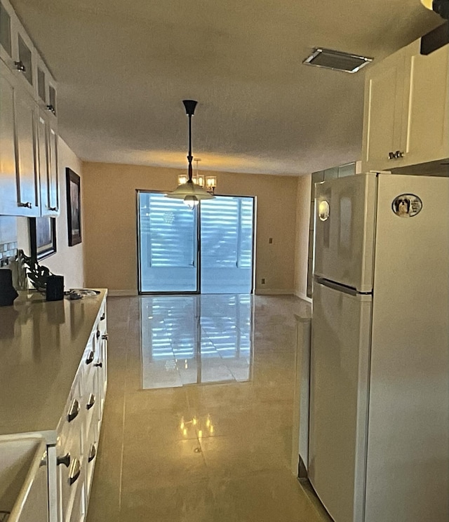 kitchen with sink, white cabinetry, decorative light fixtures, light tile patterned floors, and fridge