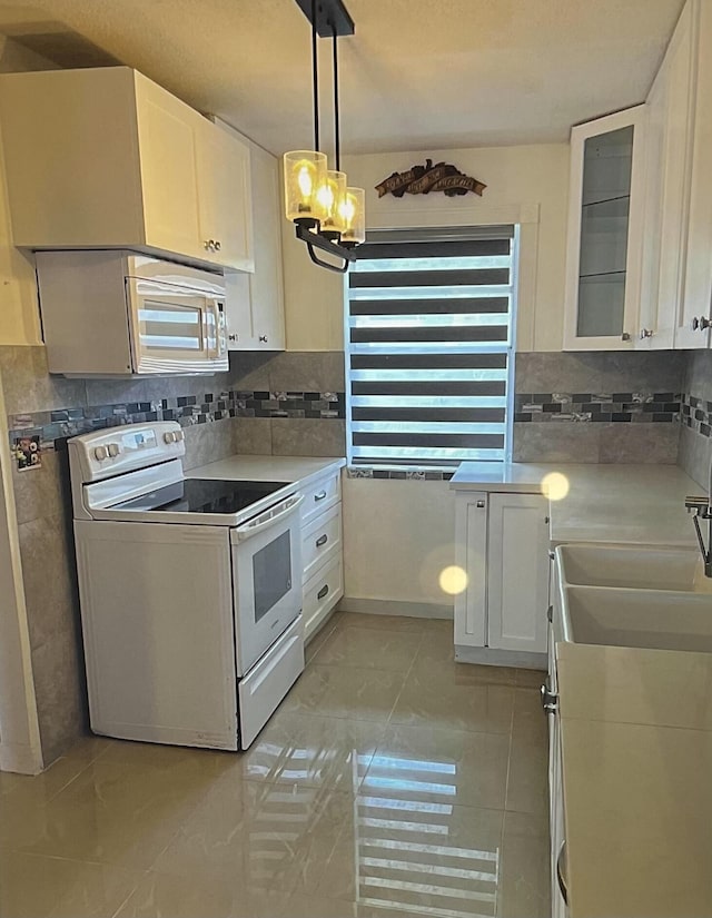 kitchen featuring pendant lighting, light tile patterned floors, white appliances, tasteful backsplash, and white cabinets