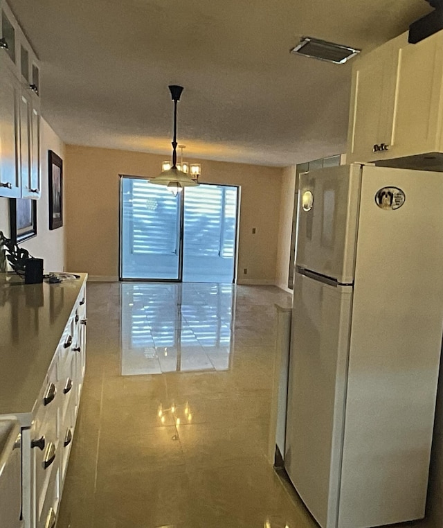 kitchen with white cabinetry, light tile patterned floors, white fridge, and pendant lighting