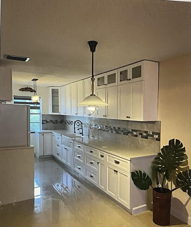 kitchen with sink, pendant lighting, white cabinets, and decorative backsplash