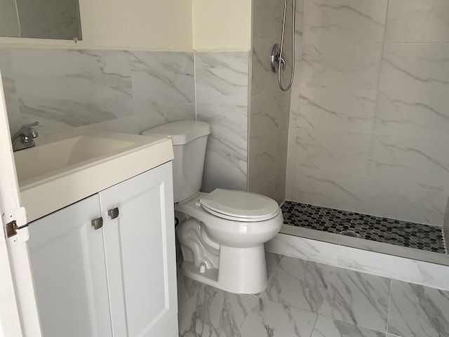 bathroom with vanity, toilet, tile walls, and a tile shower