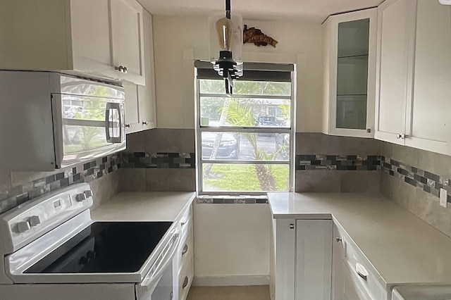 kitchen with white appliances, decorative backsplash, and white cabinets