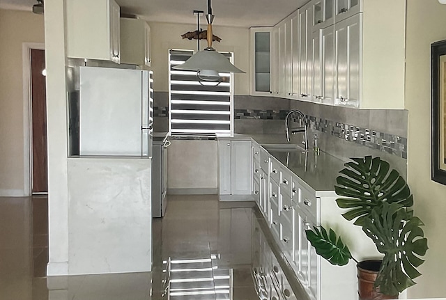 kitchen featuring tasteful backsplash, sink, and white cabinets