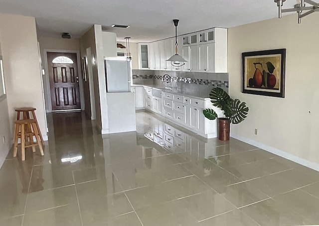 kitchen featuring pendant lighting, sink, white cabinets, backsplash, and white fridge