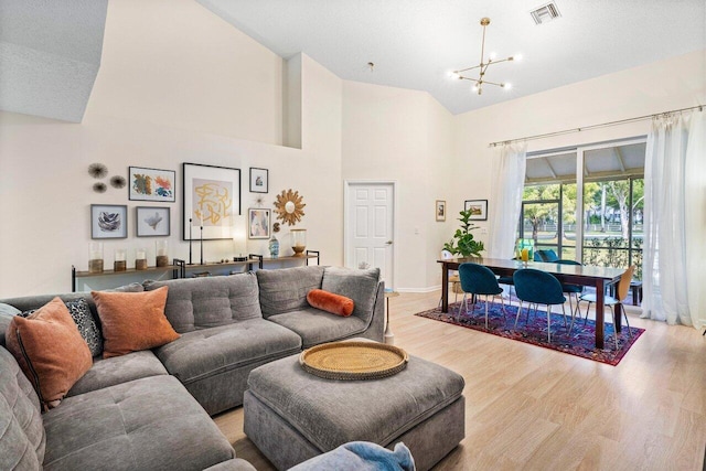 living room featuring high vaulted ceiling, a chandelier, and light hardwood / wood-style flooring