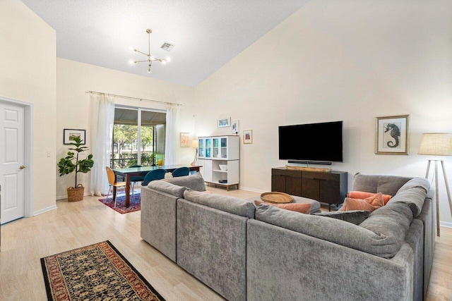 living room with high vaulted ceiling, a chandelier, and light wood-type flooring