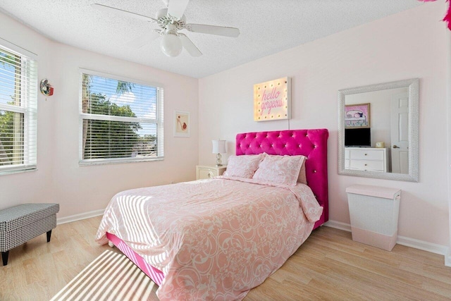 bedroom featuring ceiling fan, light hardwood / wood-style flooring, and a textured ceiling