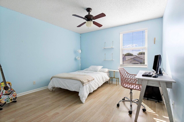 bedroom with ceiling fan, a textured ceiling, and light wood-type flooring