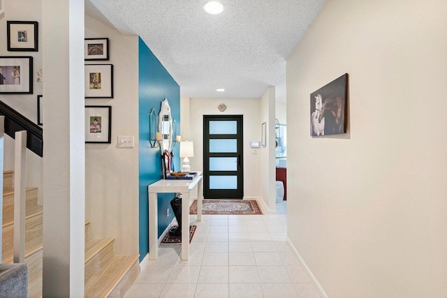 hall with light tile patterned flooring and a textured ceiling