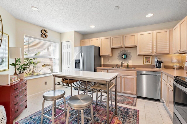 kitchen with appliances with stainless steel finishes, sink, light brown cabinets, and light tile patterned floors