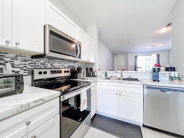 kitchen featuring sink, white cabinetry, tasteful backsplash, appliances with stainless steel finishes, and kitchen peninsula